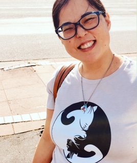 The image is a photograph of the instructor.  She is wearing a t-shirt with a yin-yang symbol in the shape of a white and black cat.
